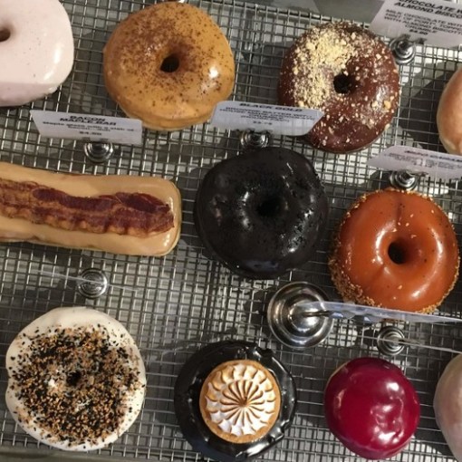 a variety of donuts sitting on top of a metal rack